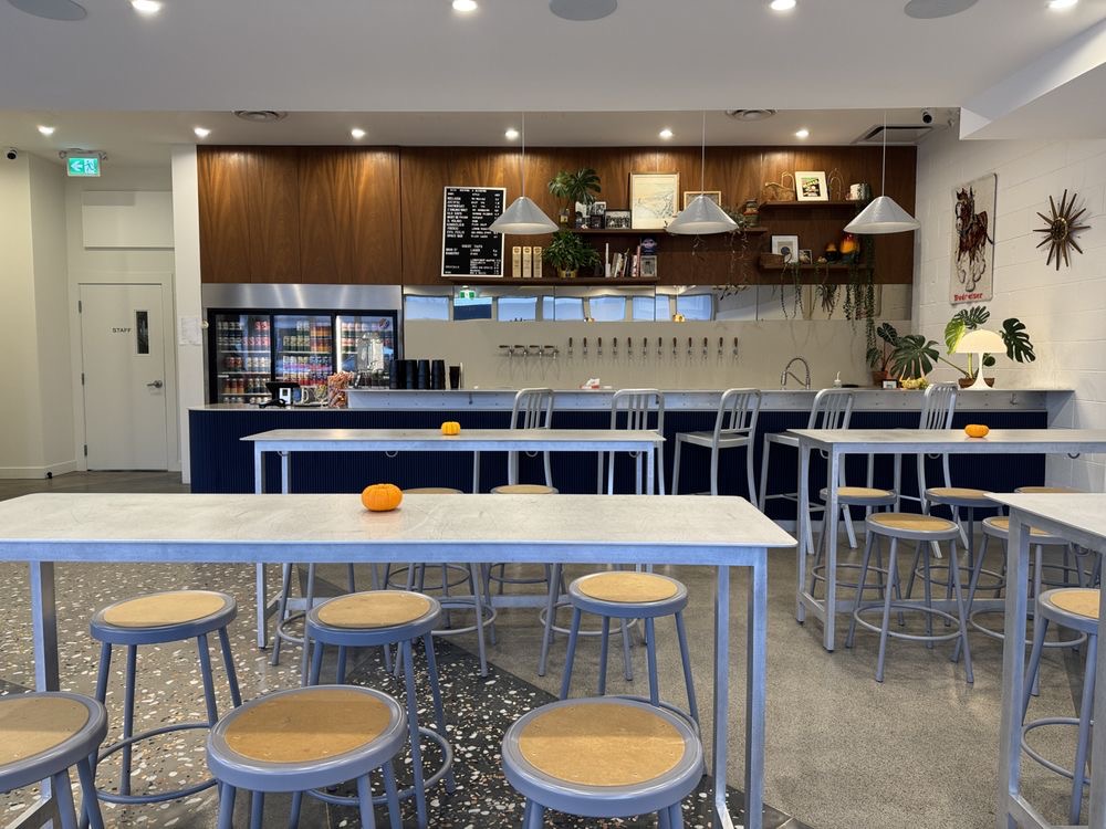 Beva Brewery interior with terrazzo floor, blue tables and stools, and bar taps.
